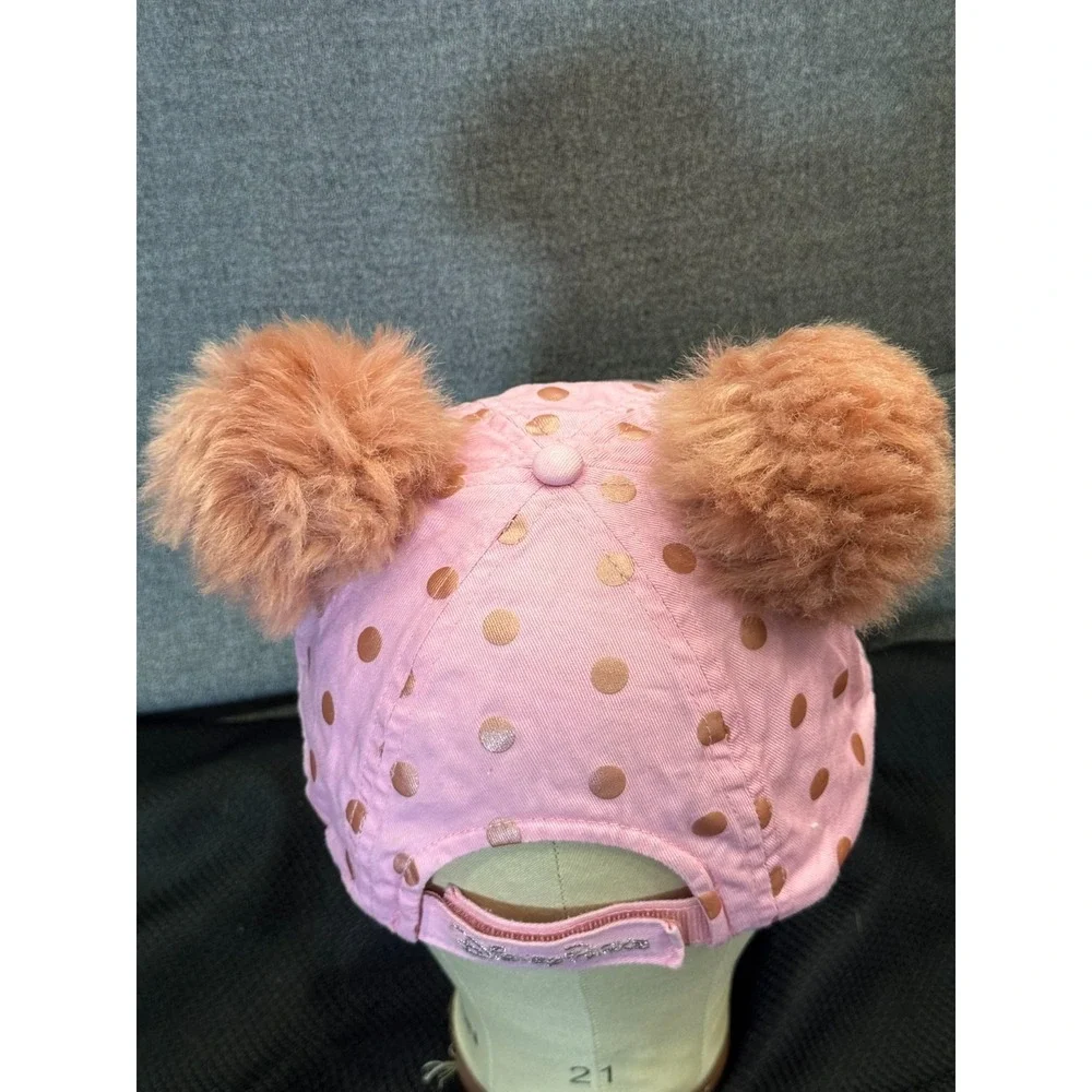 Pink polka-dot cap topped with two fluffy faux fur pom poms